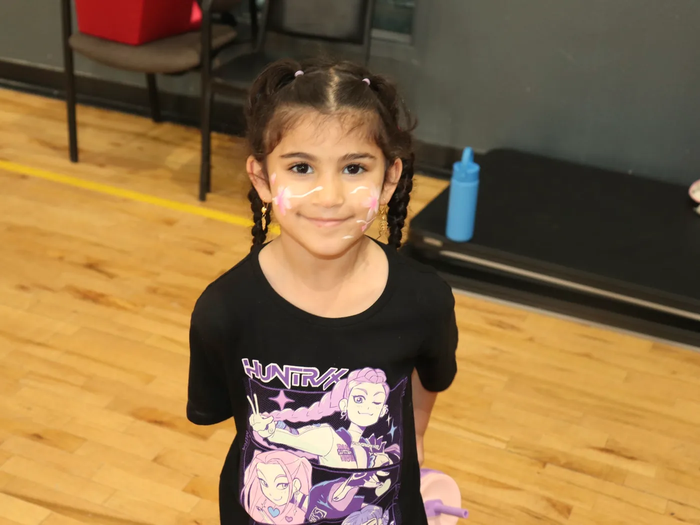 A young student with painted cheeks in the school gym